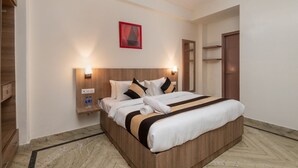 A hotel room with a wooden bed, two bedside tables with lamps, a red framed artwork on the wall, and a wooden wardrobe. - The Gleam Hotel (Gurugram)