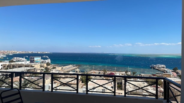 A balcony with a view of a coastal cityscape, including buildings, a marina, and the sea. - sea view apartment 06 (Red Sea Governorate)
