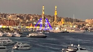 A marina with boats docked and a bridge with illuminated blue and yellow lights in the background. - sea view apartment 06 (Red Sea Governorate)