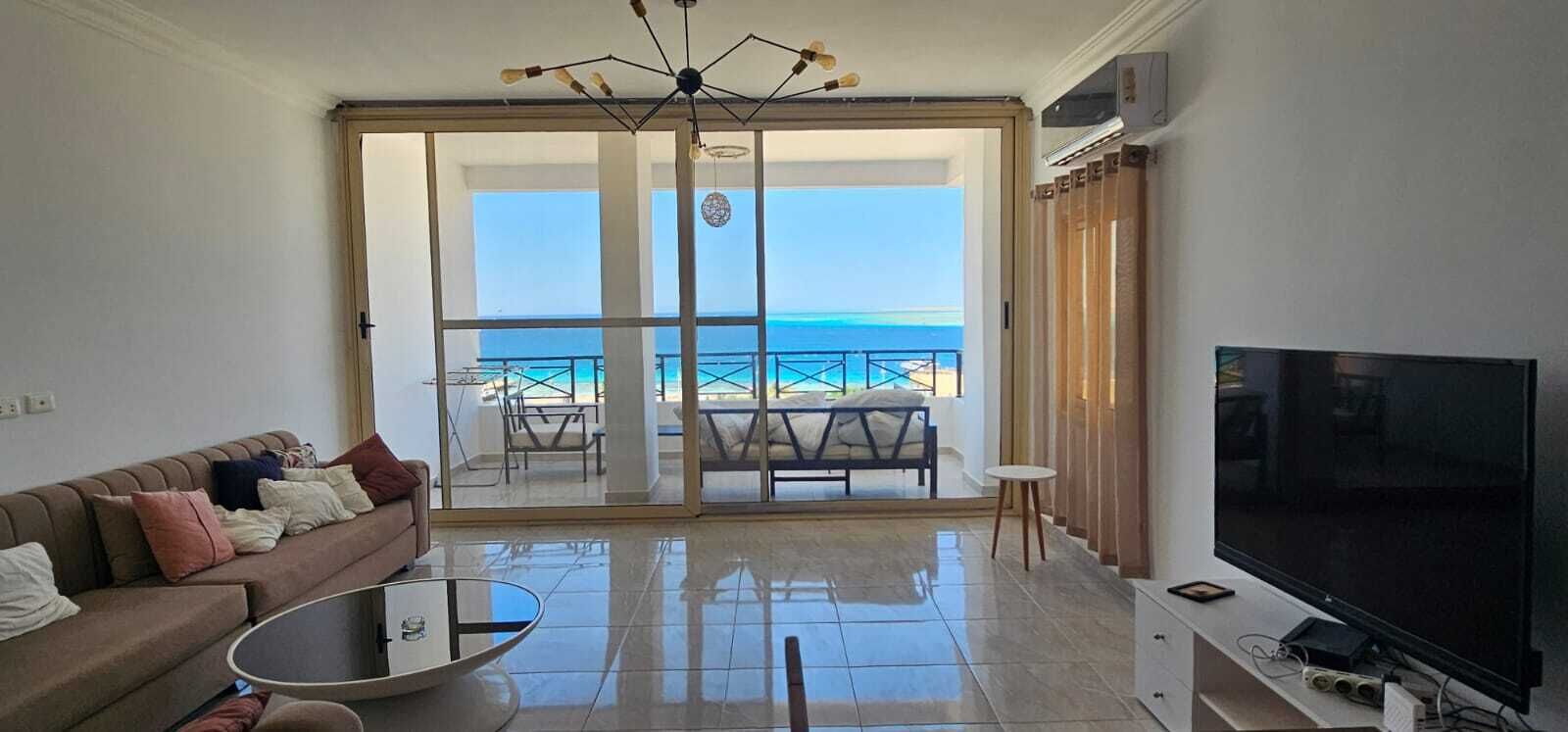 Un salon comprenant un canapé, une table basse, un téléviseur et un balcon avec vue sur la mer.