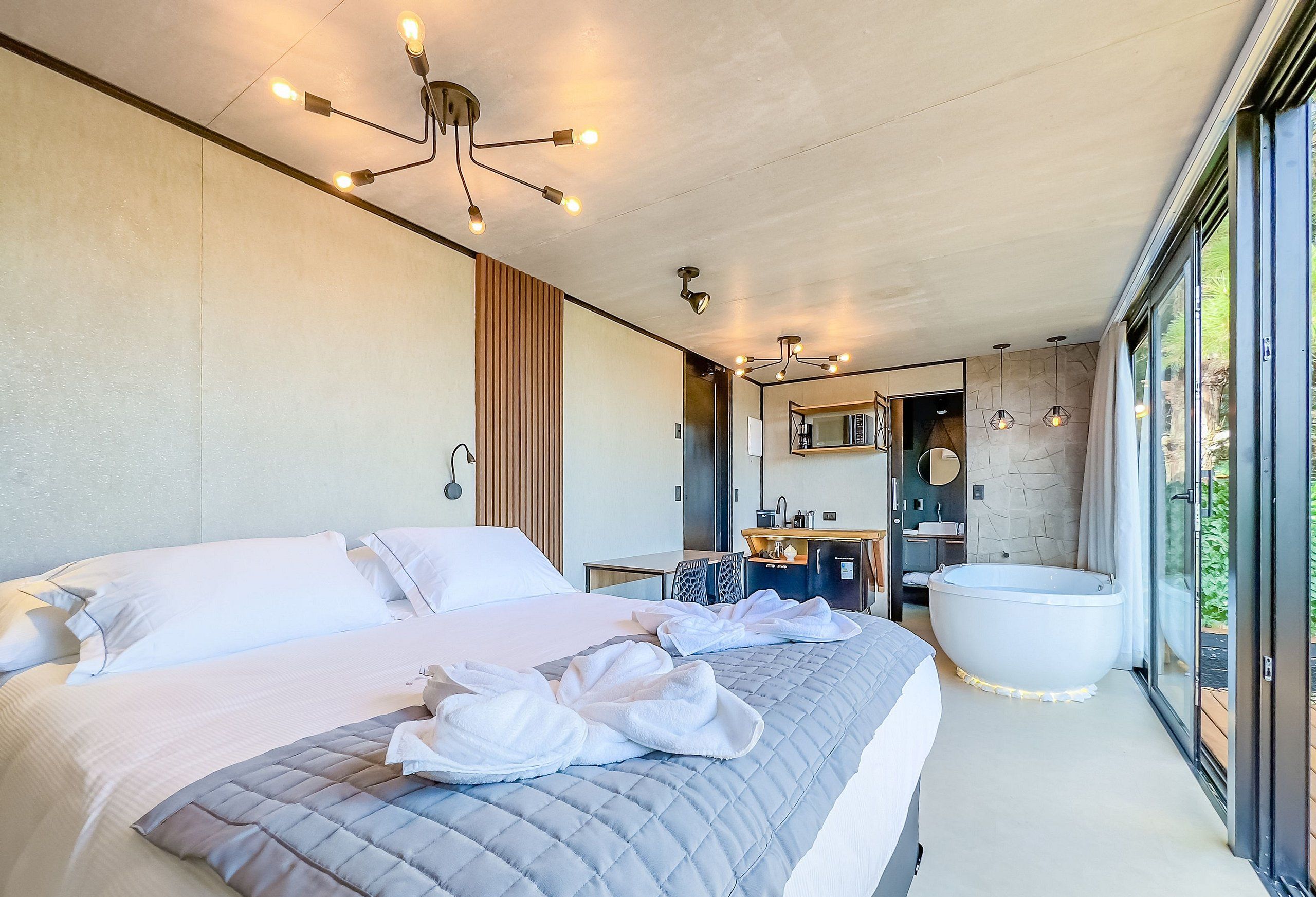 Un dormitorio moderno con una cama grande, un baño con bañera y una kitchenette.