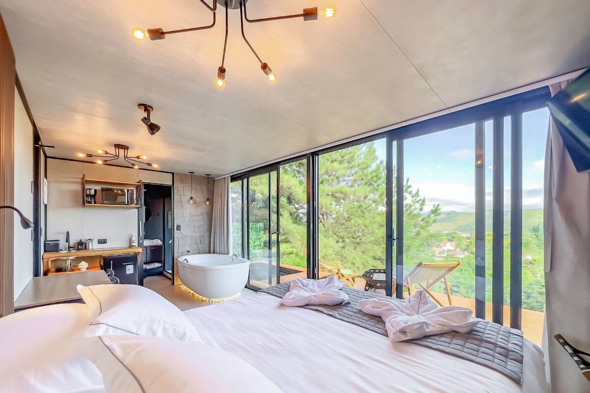 Quarto moderno com uma cama grande, uma banheira e vista para o exterior.