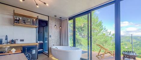 Een moderne badkamer met een vrijstaand bad, douche en een wastafel met koffiezetapparaat.