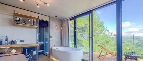 Un baño moderno con una bañera independiente, ducha y un amplio ventanal con vistas al exterior.