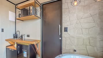 Un baño moderno con ducha integrada, tocador de madera y pared de piedra.