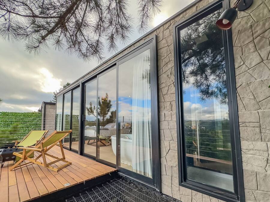 A modern outdoor deck with a wooden floor, a grill, and two lounge chairs.