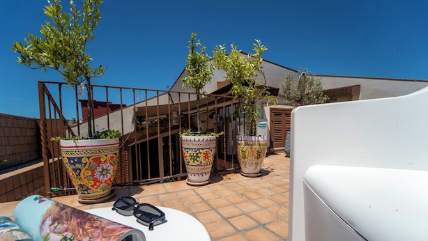 A patio with potted plants, a white table, and a metal fence. - Casa Raffaela with Terrace by Wonderful Italy (Naples)