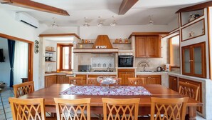 A spacious kitchen with wooden cabinets, a central island, and a dining area with a table and chairs. - Casa Raffaela with Terrace by Wonderful Italy (Naples)