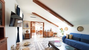 A spacious living room with a high ceiling, a blue sofa, a wooden coffee table, and a tiled floor. - Casa Raffaela with Terrace by Wonderful Italy (Naples)