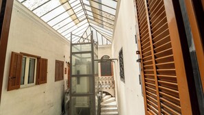 A narrow corridor with a glass ceiling, wooden shutters, and a metal staircase. - Casa Raffaela with Terrace by Wonderful Italy (Naples)
