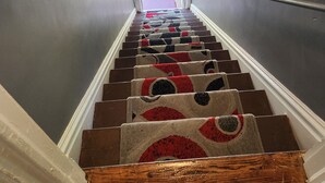 Una escalera con alfombra estampada y escalones de madera que conducen a un espacio al aire libre.