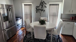 Una cocina moderna con electrodomésticos de acero inoxidable, una mesa de comedor con sillas y un ventilador de techo.