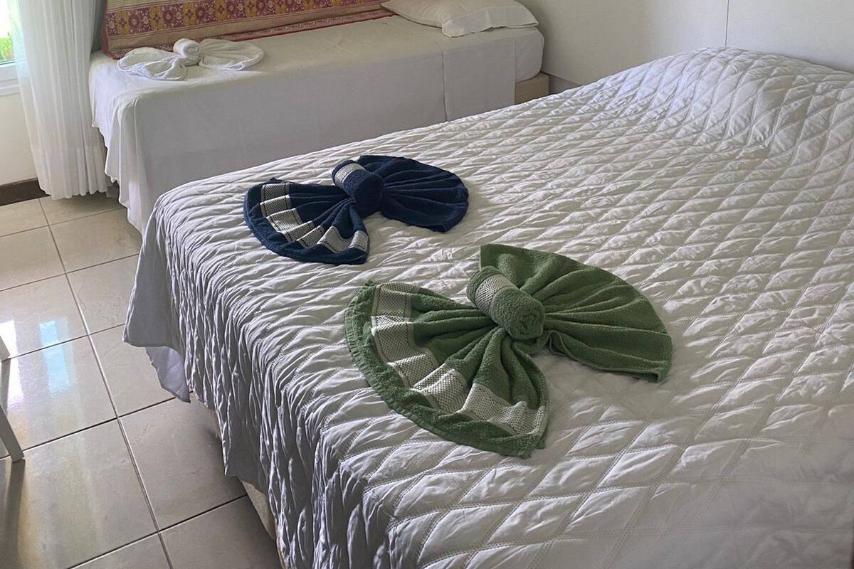 Ein Hotelzimmer mit zwei Betten, einem gemusterten Kopfteil und Bildern an den Wänden.