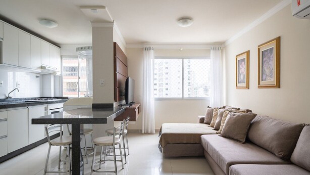 A modern kitchen with a dining area, a sofa, and a TV. - EAC Apto 2min praia Balneário Camboriú (Balneário Camboriú)