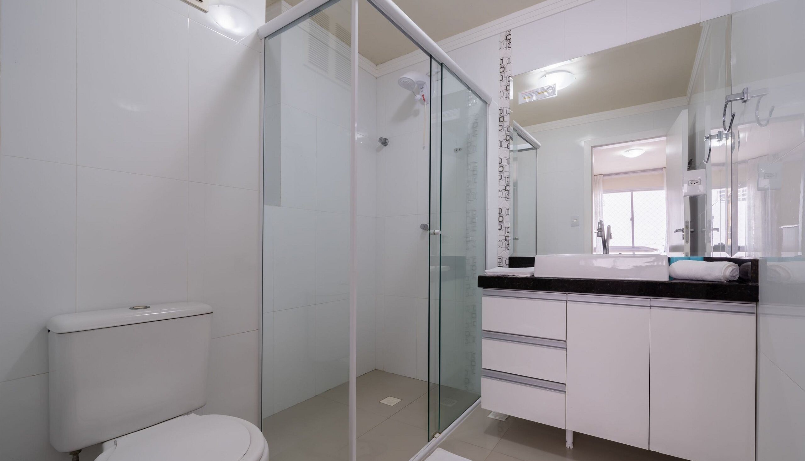 Un baño moderno con ducha envuelta en vidrio, inodoro y tocador con espejo.