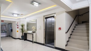 A hotel lobby with a reception desk, an elevator, a staircase, and a fire alarm. - EAC Apto 2min praia Balneário Camboriú (Balneário Camboriú)