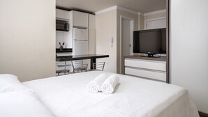 A hotel room with a bed, a TV, a kitchenette, and a dining area. - EAC Apto 2min praia Balneário Camboriú (Balneário Camboriú)