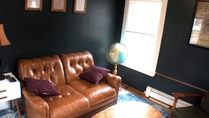 A room with a brown leather sofa, two purple pillows, a globe on a stand, and a framed picture on the wall. - Cozy Pet Friendly House Next To Train (Canton)