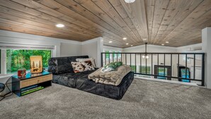 A bedroom with a wooden ceiling, a bed with a blanket, a bedside table with a lamp, and a view of the outdoors. - Tiny Bear Paw-relax, unwind and recharge (Mentone)