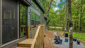 A cabin with a wooden deck, large windows, and a forested backdrop. - Tiny Bear Paw-relax, unwind and recharge (Mentone)