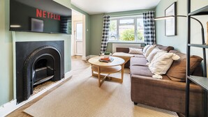 A living room with a fireplace, a sofa, a coffee table, and a TV mounted on the wall. - Link Road House By REDWOOD STAYS (Alton)