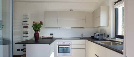 A modern kitchen with white cabinetry, a built-in oven, and a large window providing natural light.