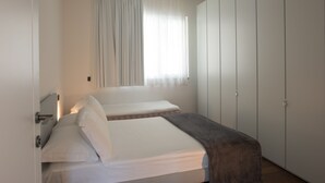 A bedroom with two beds, a window with curtains, and a wardrobe. - Villa Olivo (Blevio)