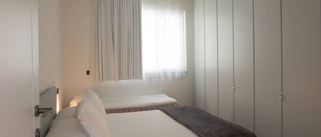 Une chambre avec deux lits, une fenêtre avec des rideaux et une armoire.