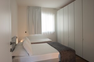 Un dormitorio con dos camas, una ventana con cortinas y un armario.