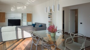 A modern living room with a sofa, a glass dining table, and a bookshelf. - Villa Olivo (Blevio)