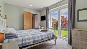 Een slaapkamer met een bed, nachtkastje en een televisie aan de muur.