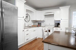 Eine moderne Küche mit weißen Schränken, einem Edelstahlkühlschrank und einer Holztheke.