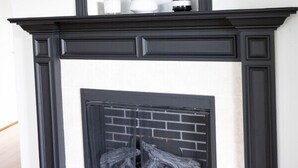 A black-framed fireplace with a white mantel, a TV mounted above it, and two shelves with potted plants. - Modern 2BR Condo in Gatlinburg (Gatlinburg)