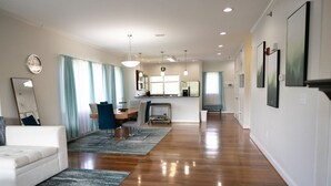 A spacious living area with a wooden floor, a white sofa, a dining table with chairs, and a kitchen in the background. - Modern 2BR Condo in Gatlinburg (Gatlinburg)