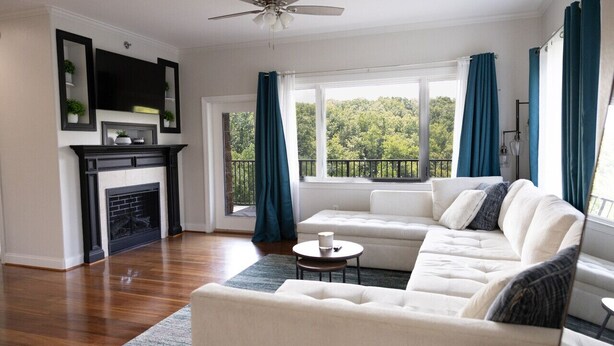 A living room with a fireplace, white sofa, and a view of a balcony with curtains. - Modern 2BR Condo in Gatlinburg (Gatlinburg)