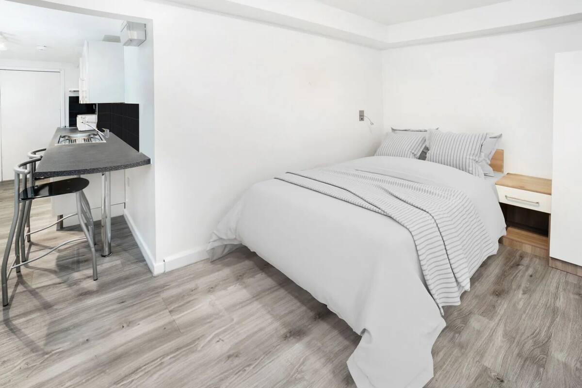 A modern bedroom with a bed, bedside table, and a small desk with a chair.