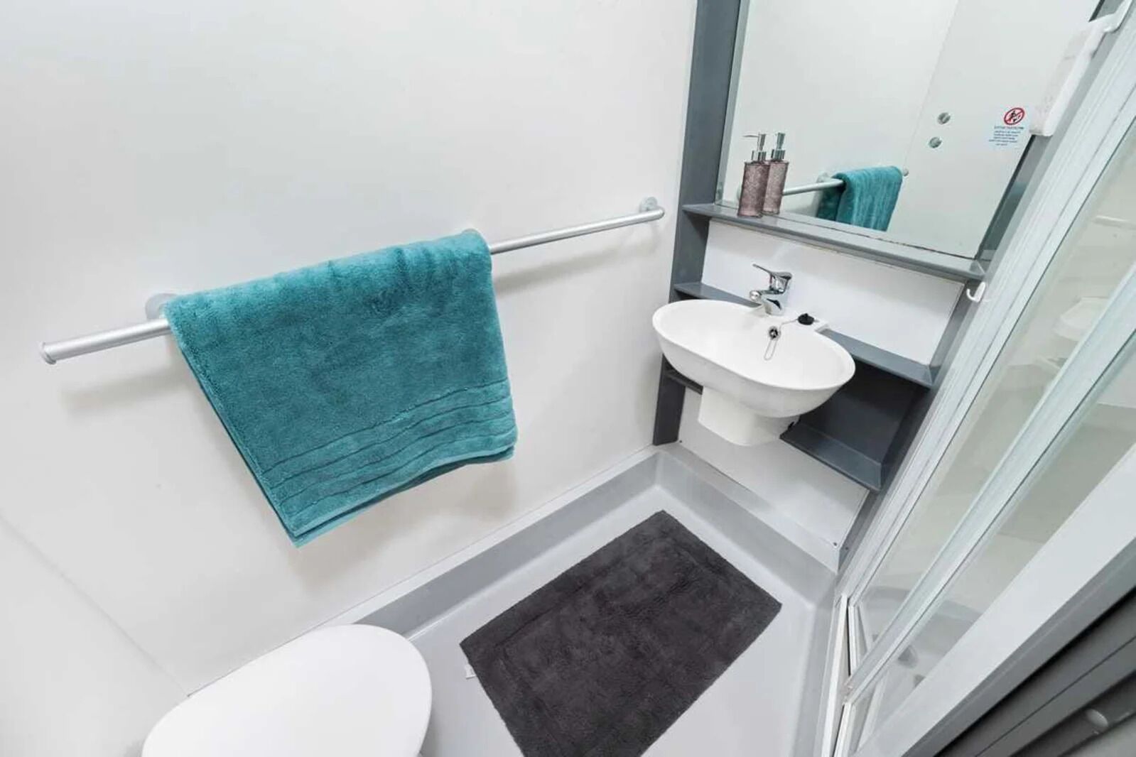 Ein kleines Badezimmer mit Toilette, Waschbecken und einem Handtuchhalter mit blauem Handtuch.