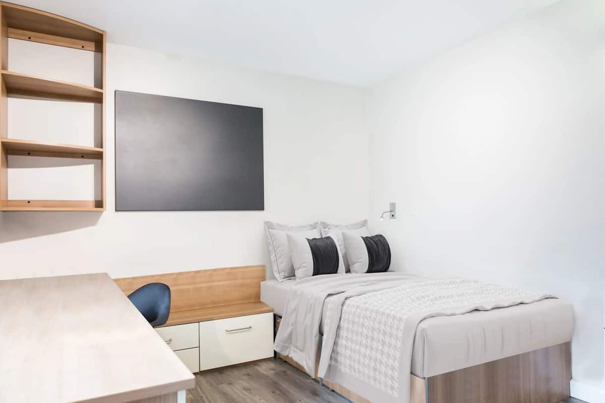 A bedroom with a bed, bedside table, and a wall-mounted shelf.
