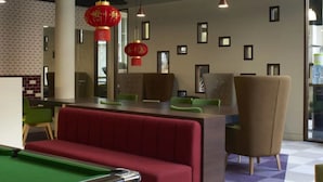 A modern indoor space with a pool table, red seating, and pendant lighting. - For Students Only Chapter Highbury I in London (London)