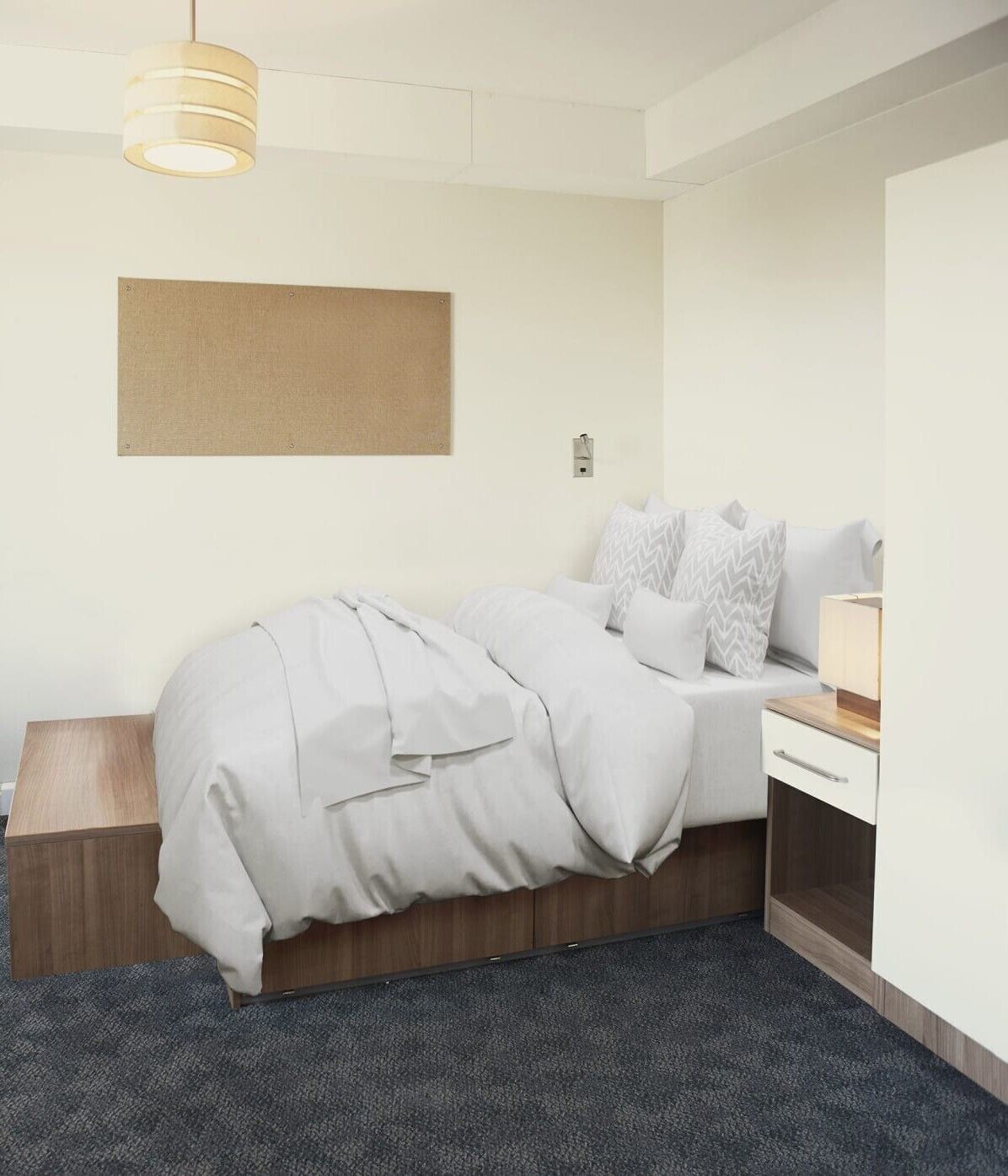 A modern hotel room with a neatly made bed, a bedside table, a lamp, and a large window.