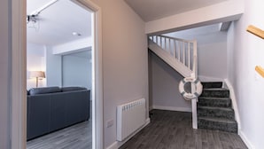 A modern interior with a staircase, grey carpeted stairs, a grey sofa, and a white radiator. - Maritime House II (Hull)