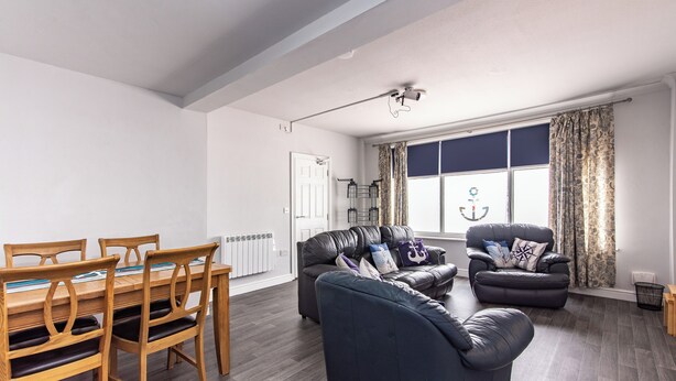 A living room with a dining table, chairs, a sofa, and a window with curtains. - Maritime House II (Hull)