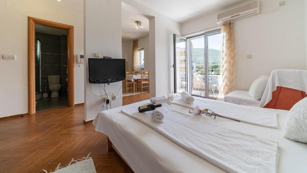 Hotellihuone, jossa on kaksi sänkyä, televisio ja parveke, jolta on näkymä.
