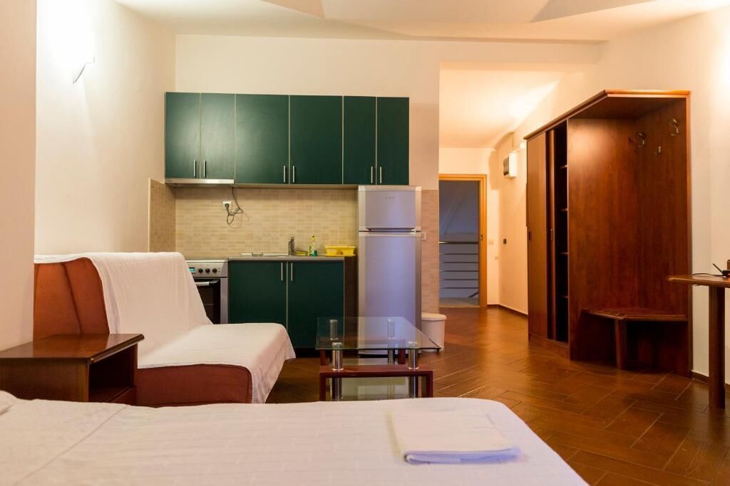 Een compacte hotelkamer met een kitchenette, een bed, een klein tafeltje en een zithoek.
