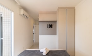 Una habitación de hotel moderna con una cama, una toalla, un aire acondicionado de pared y una puerta corredera.