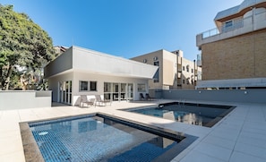 Un área moderna de piscina al aire libre con un edificio en el fondo.