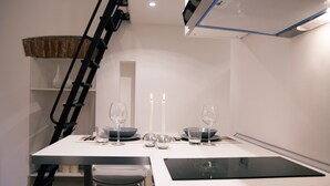 A modern dining area with a white table, two chairs, and a black induction cooktop. - Italianway - Copernico I (Milan)