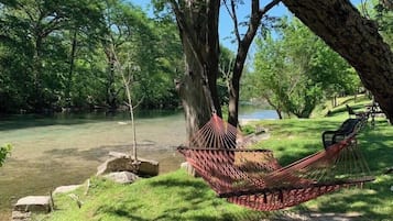 Relax in a serene forest setting, surrounded by lush greenery and a tranquil body of water.