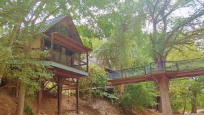 A wooden house with a balcony and a bridge connecting to another structure.