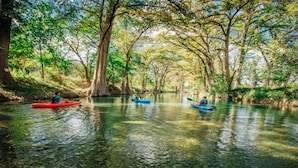 A calm river with kayaks, surrounded by trees and clear water.